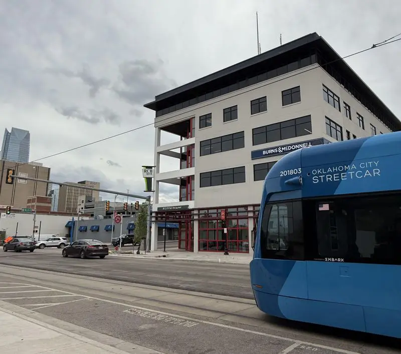 Blue streetcar in urban cityscape with buildings.